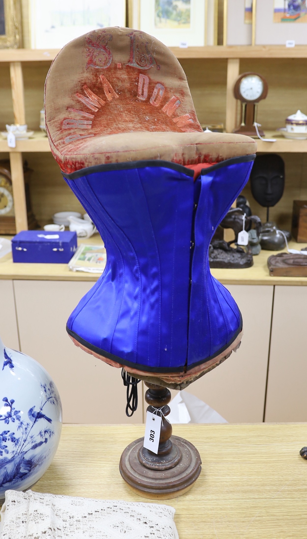 An early 20th century 'Prima Donna' red velvet corset mannequin on turned stand with a contemporary blue satin corset, mannequin, 79cm high